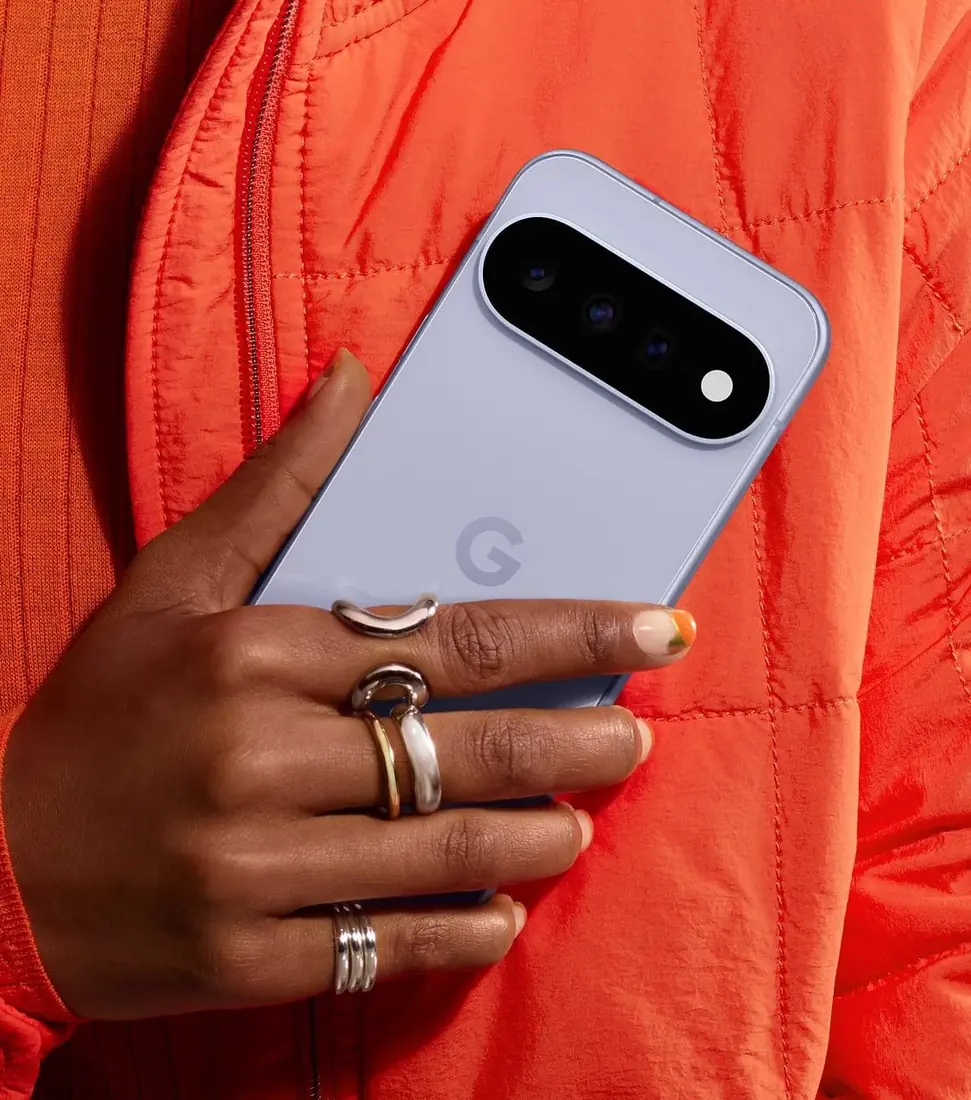 Google Pixel 11 — Back of the Frost Google Pixel 11, showing the three-camera island. The manufacturer store photo shows the phone held in a hand.